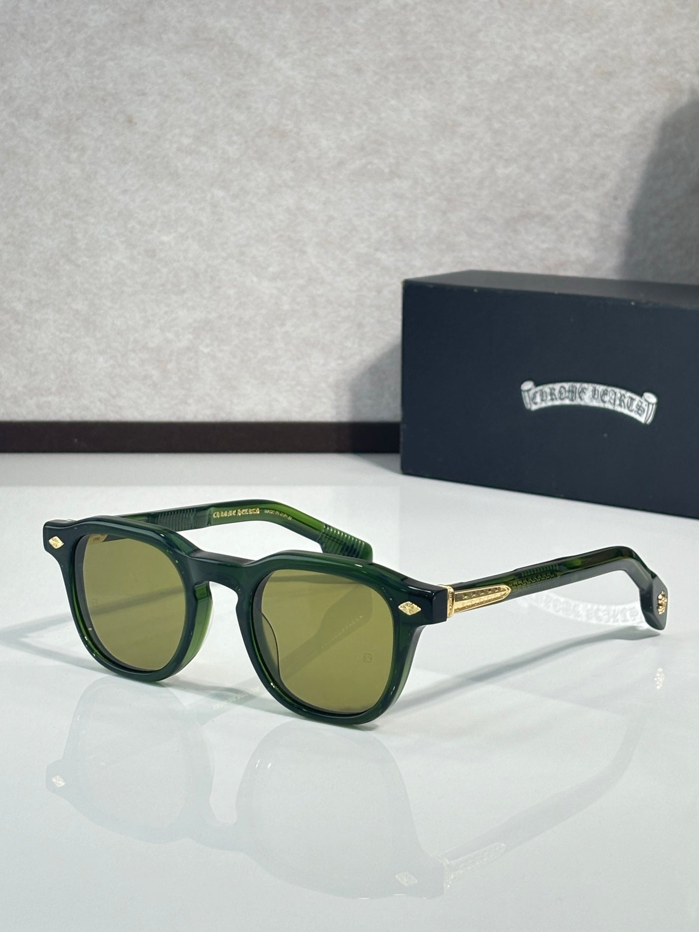 Green round sunglasses with green lenses and gold-tone temple accents