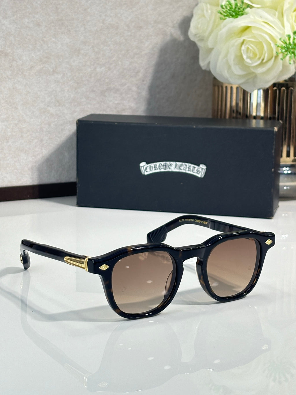 Navy cat-eye sunglasses with brown lenses, gold-tone arms, and rhinestone logo.