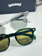 Clear chrome and green sunglasses close-up, with patterned temple details.