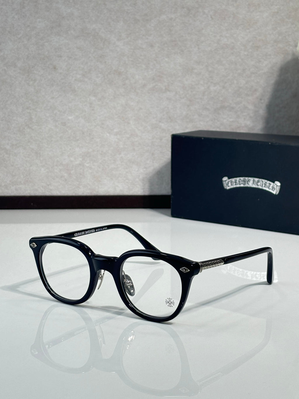 Black round eyeglass frames with clear lenses and metal side arms