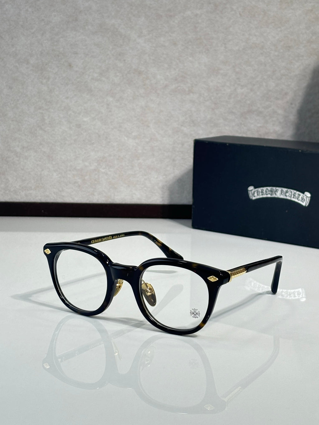 Black round eyeglass frames with clear lenses and gold-tone temples