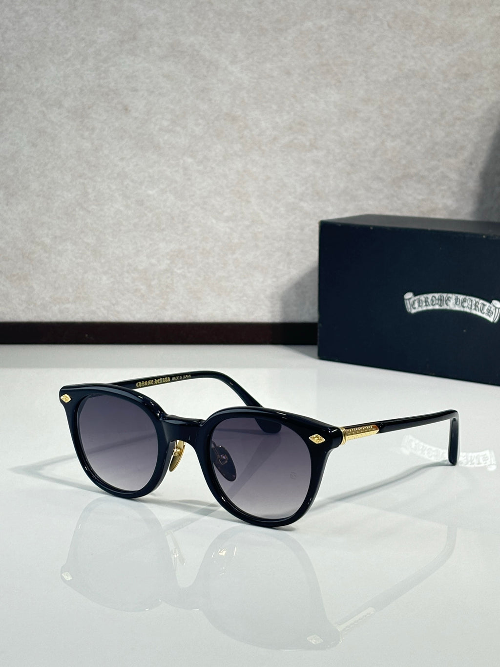 Black round eyeglass frames with dark lenses and gold-tone temples