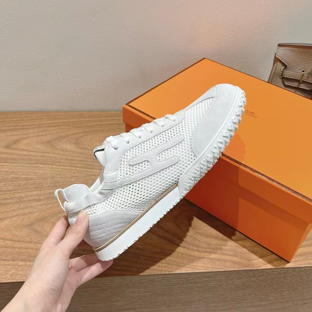 White Hermes unisex sneakers held in hand, lace-up, perforated upper, textured sole