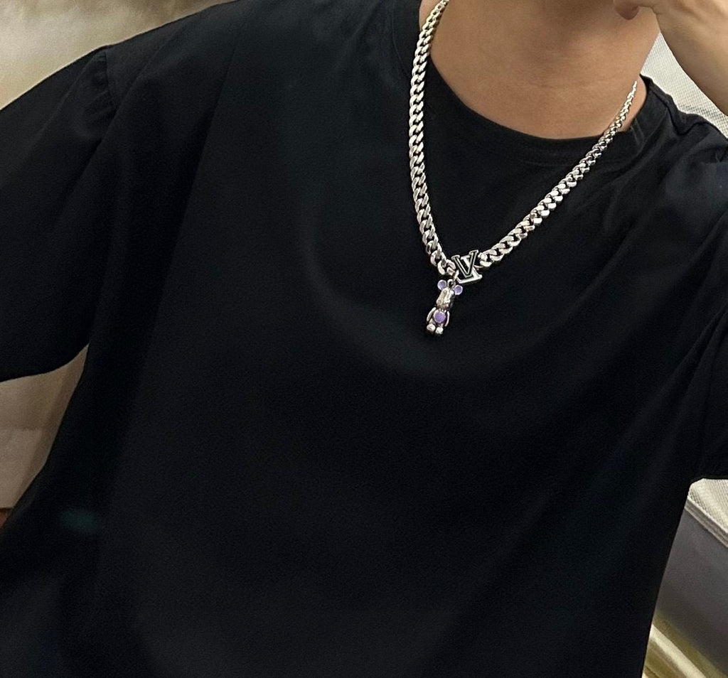Louis Vuitton silver chain necklace on black shirt, green V charm with purple stones