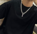 Louis Vuitton silver chain necklace on black shirt, green V charm with purple stones