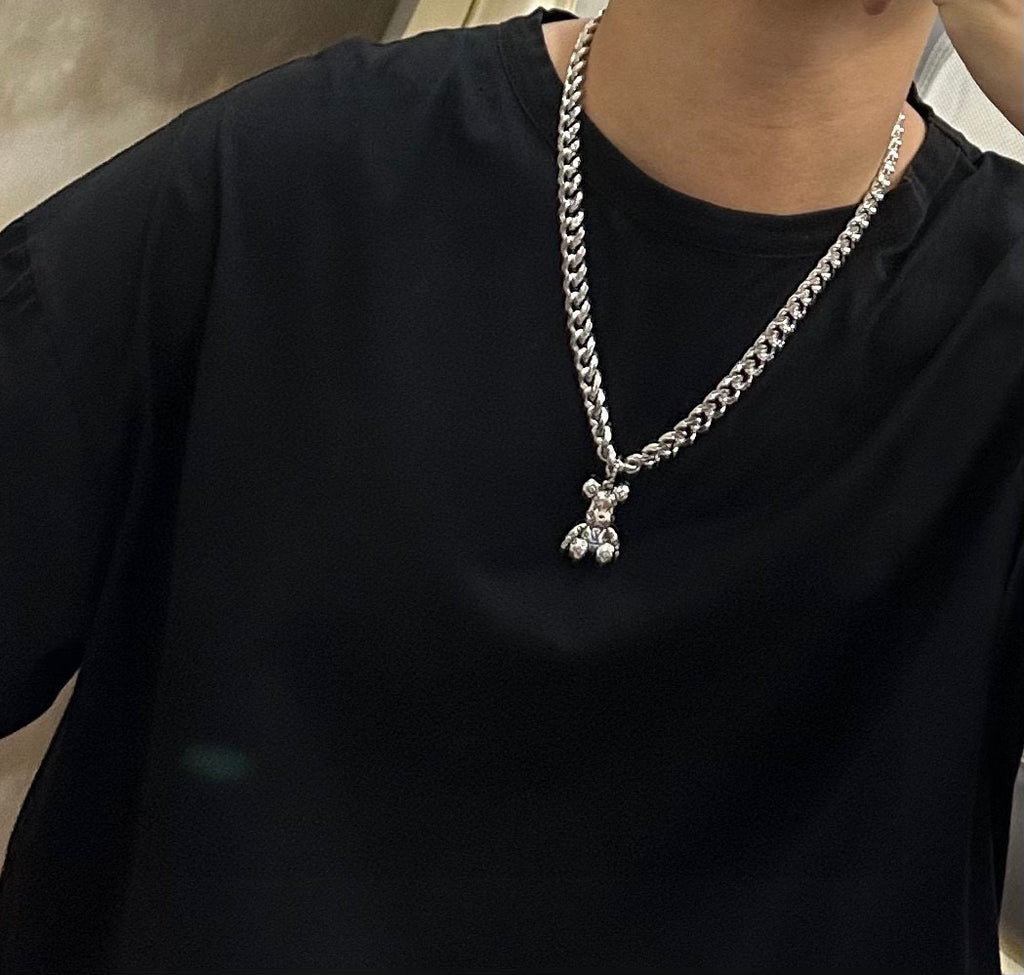 Silver chain necklace with small charm pendant, worn on black crewneck shirt