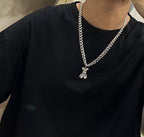 Silver chain necklace with small charm pendant, worn on black crewneck shirt