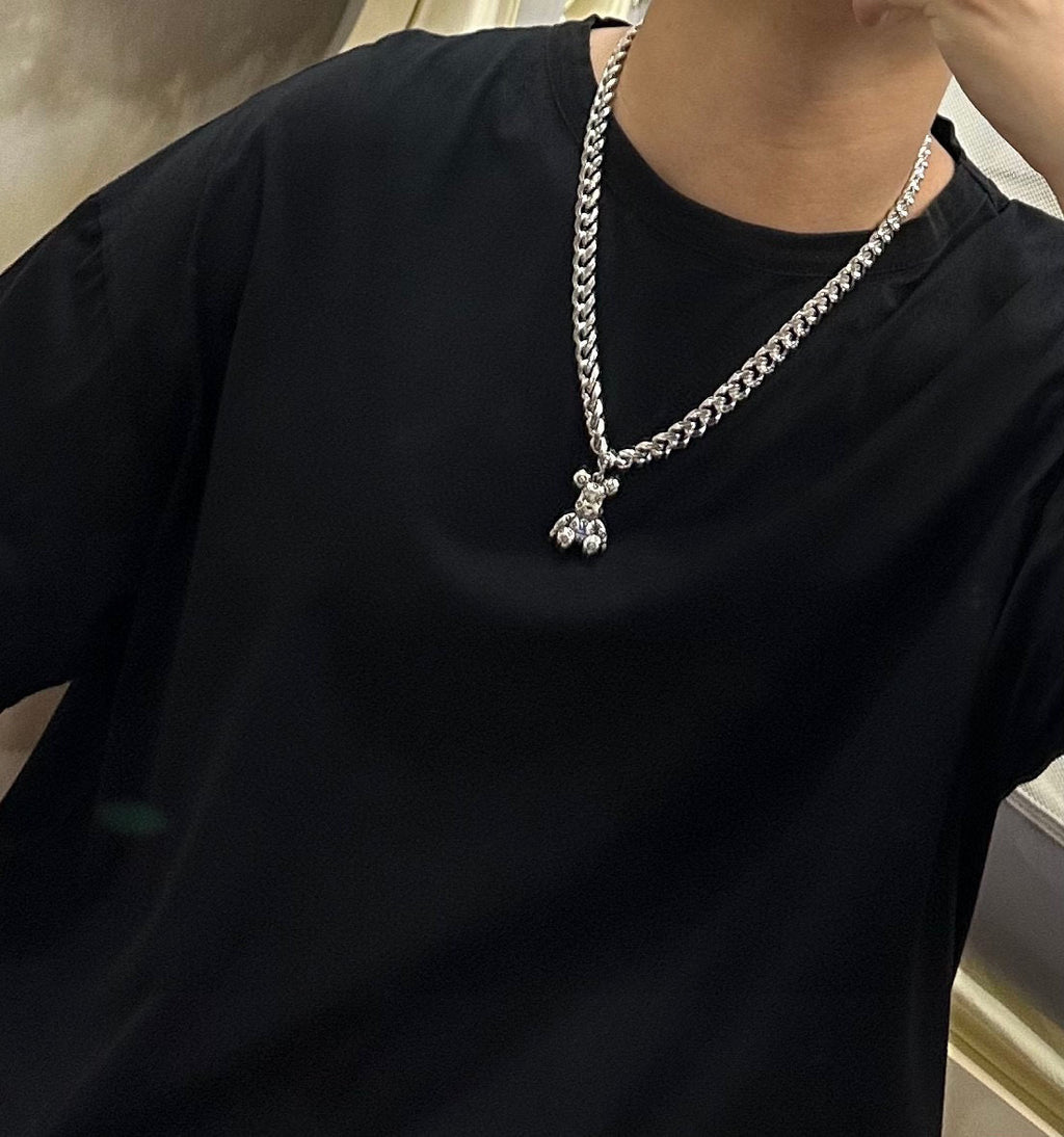 Silver chain necklace with small charm pendant, worn on black crewneck shirt