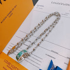 Silver-tone chain necklace with green enamel pendant on accessory card