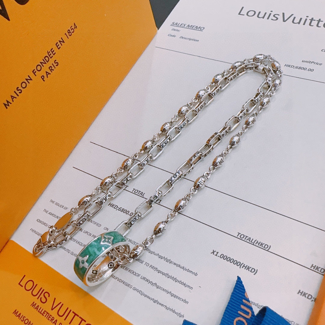 Silver-tone chain necklace with green enamel pendant on accessory card