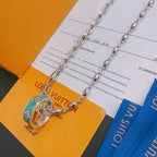 Silver-tone chain necklace with green enamel charm pendant detail