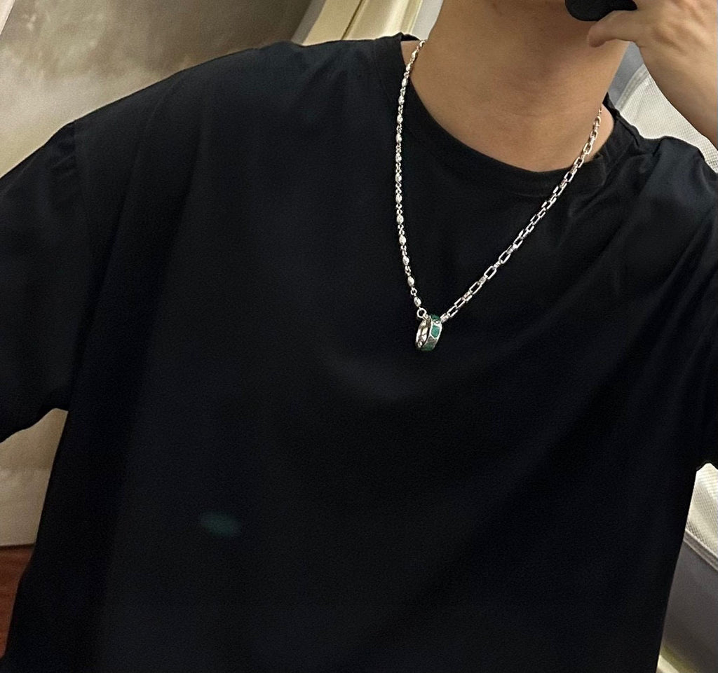 Silver-tone chain necklace worn with green enamel pendant