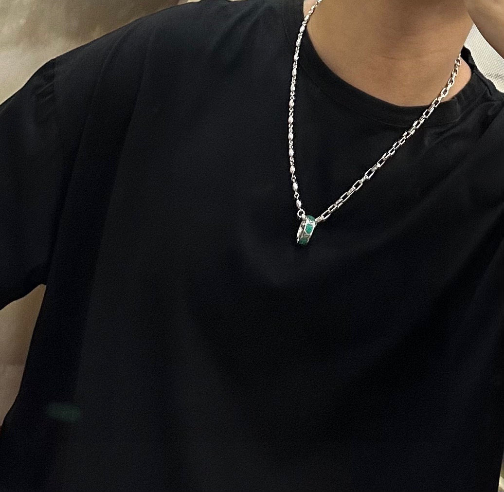 Silver-tone chain necklace with green pendant hanging at the chest