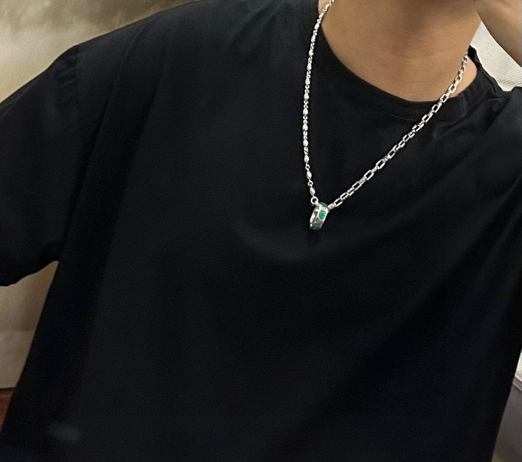 Silver-tone chain necklace worn with small green pendant