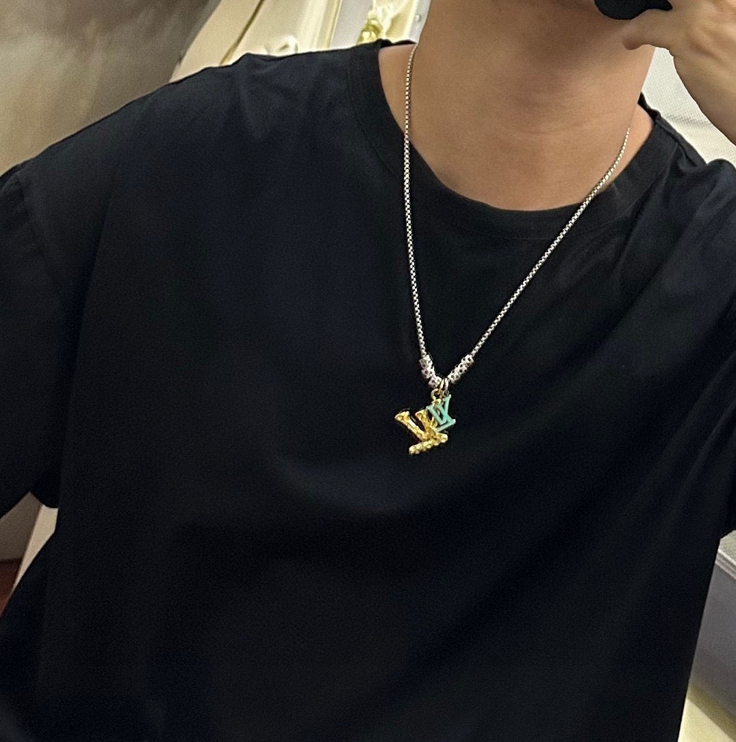 Louis Vuitton necklace worn: silver chain with gold LV star pendant on black shirt