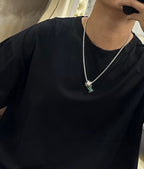 Silver-tone chain necklace with multicolor square charm pendant, worn on a black top.