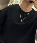 Silver-tone chain necklace with multicolor square charm pendant on a black top.