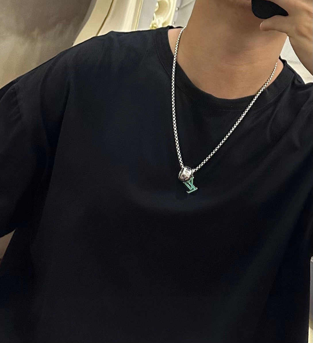 Silver-tone chain necklace with multicolor charm pendant hanging on a black top.