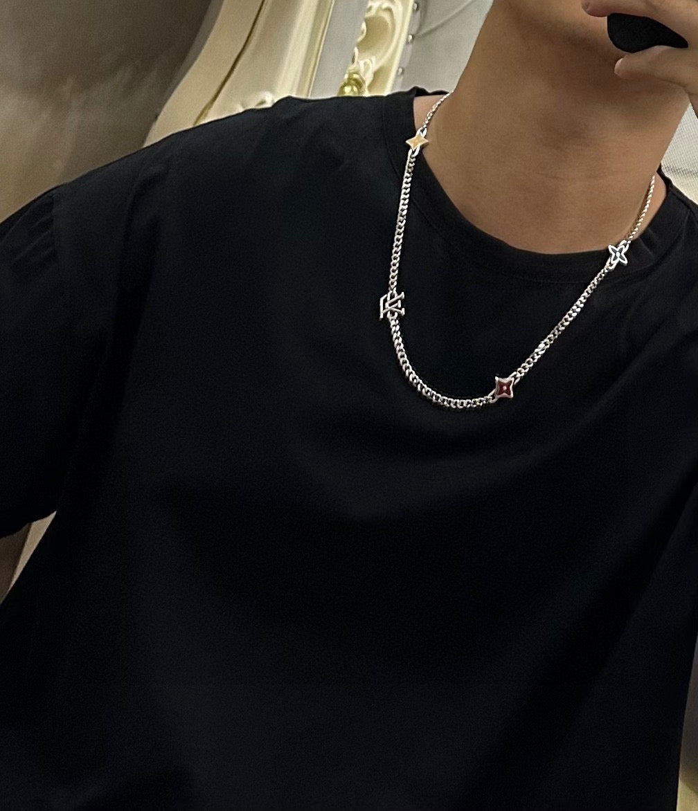 Silver-tone charm necklace worn over black crewneck top with star charms