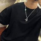 Silver-tone chain necklace with green star pendant on black crewneck T-shirt