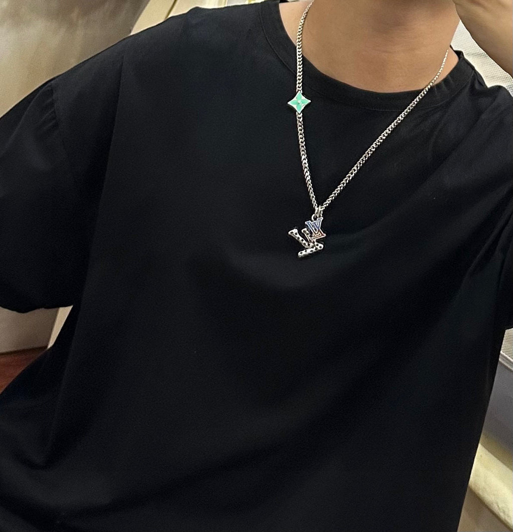 Silver-tone chain necklace with green star charm on black crewneck T-shirt