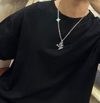 Silver-tone chain necklace with green star charm on black crewneck T-shirt