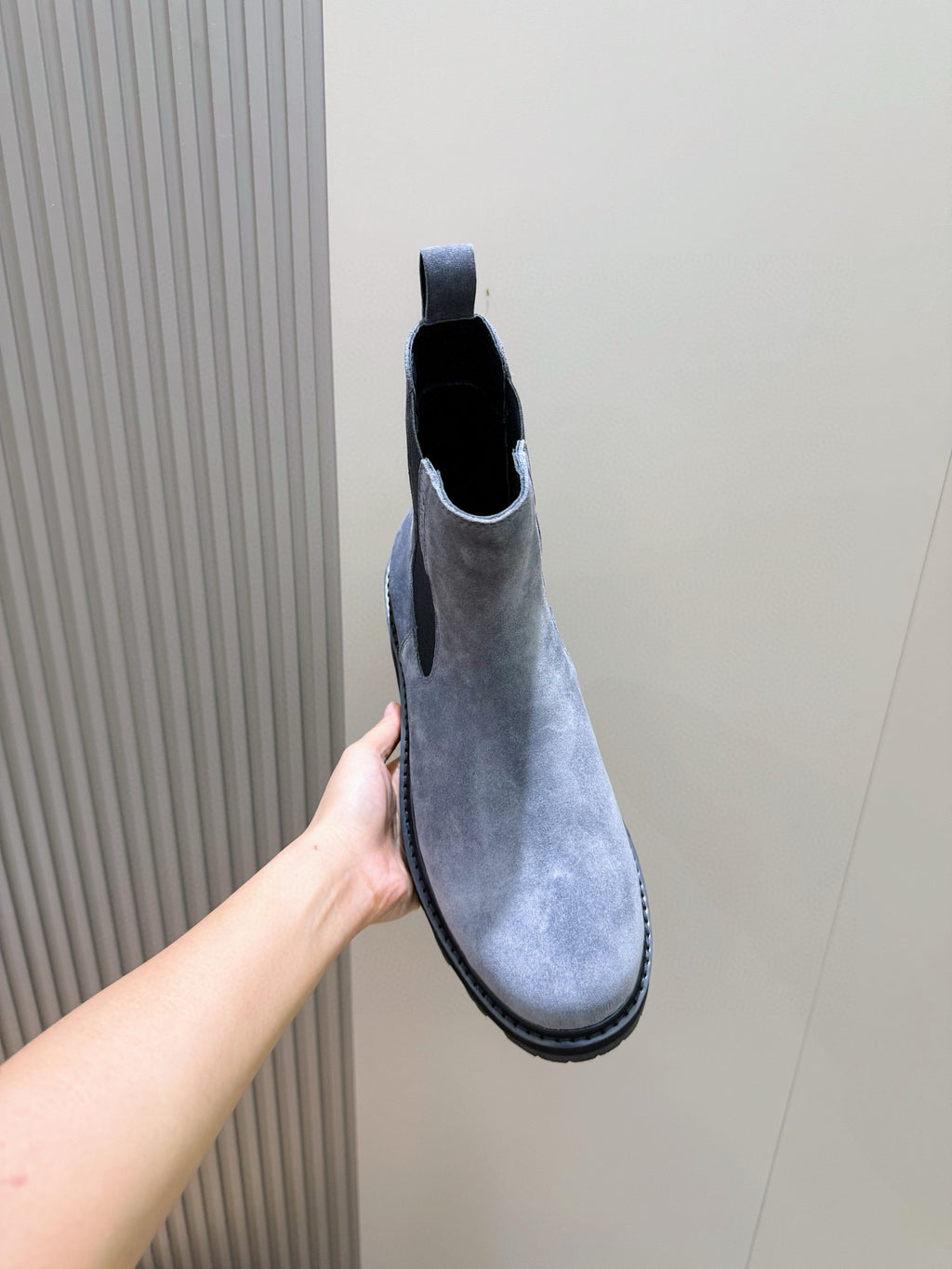 Moncler suede Chelsea boot with elastic gore and dark rubber sole, held up by hand