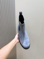 Moncler suede Chelsea boot with elastic gore and dark rubber sole, held up by hand