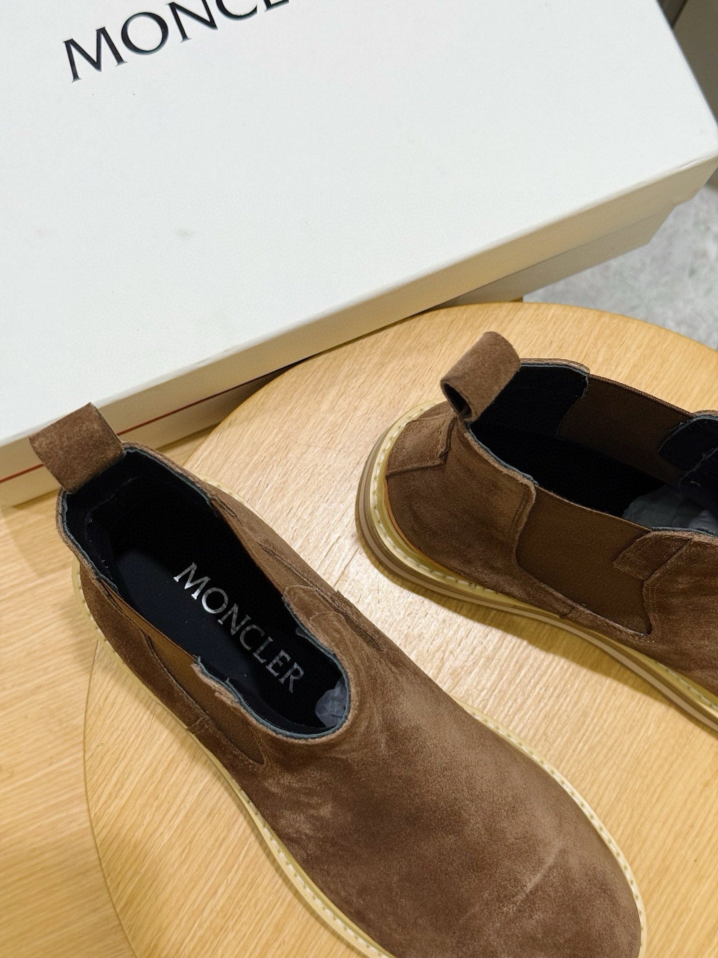 Moncler brown suede slip-on Chelsea boots with black interior, on wooden stand
