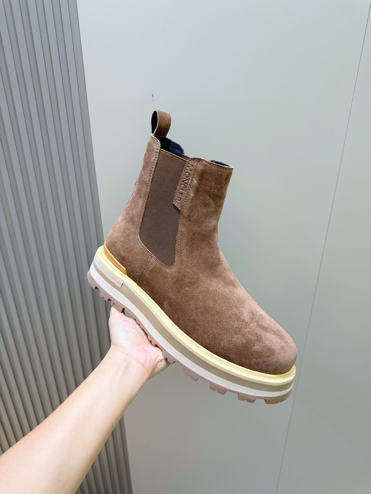 Moncler brown suede Chelsea boot held in hand, elastic side panel and cream sole