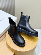 Two black Chelsea boots on a round pedestal, side elastic and chunky sole