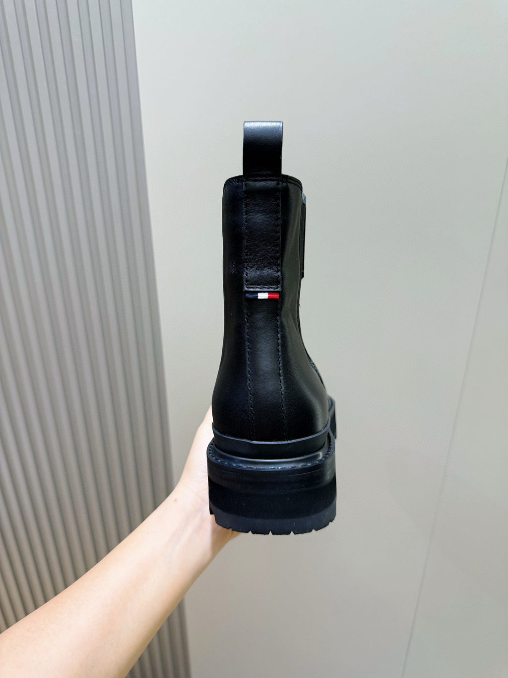 Black Chelsea boot on hand, back pull tab and red/white flag detail on side