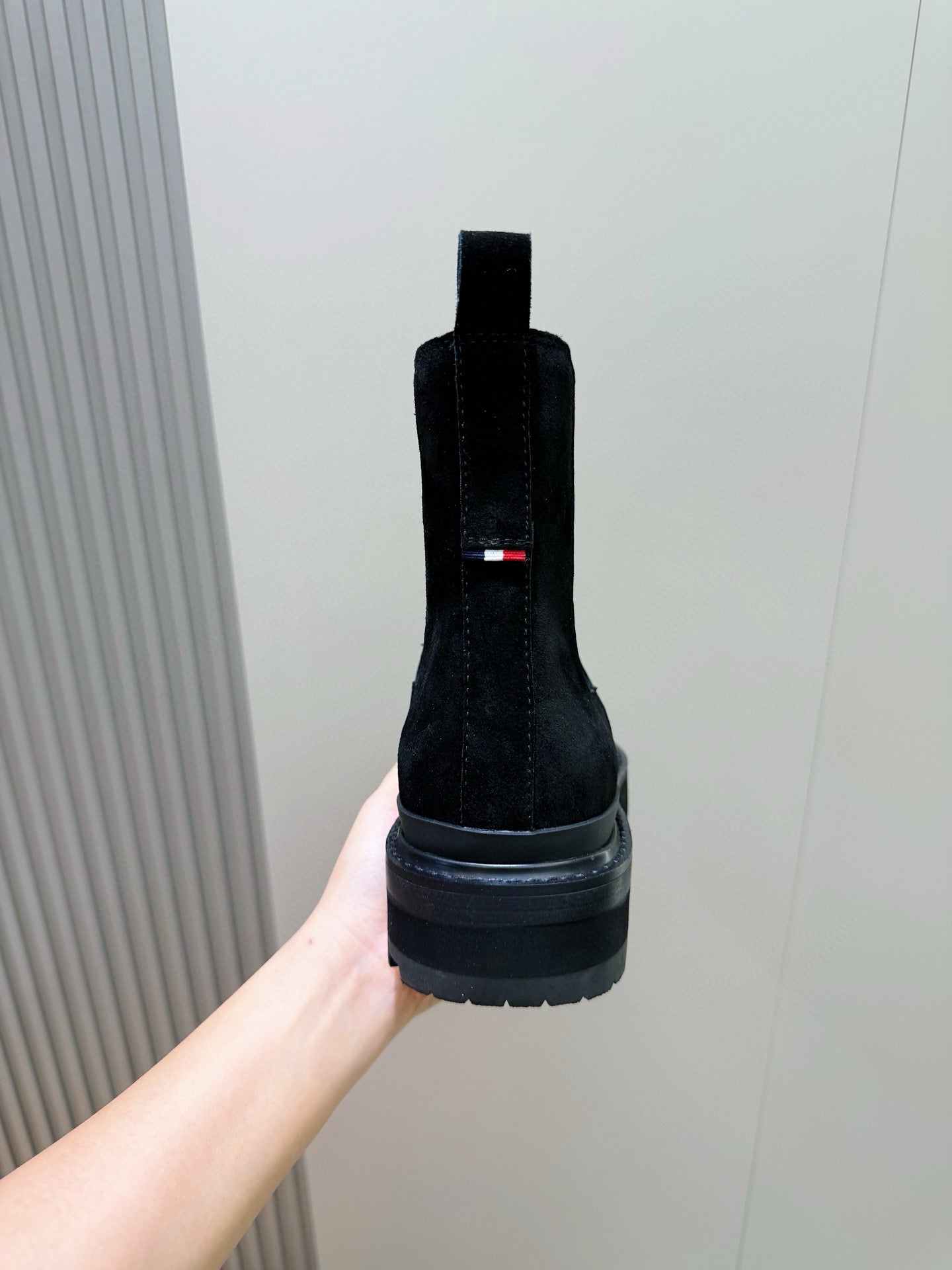 Black suede Chelsea boot back view with pull tab and stacked rubber sole.