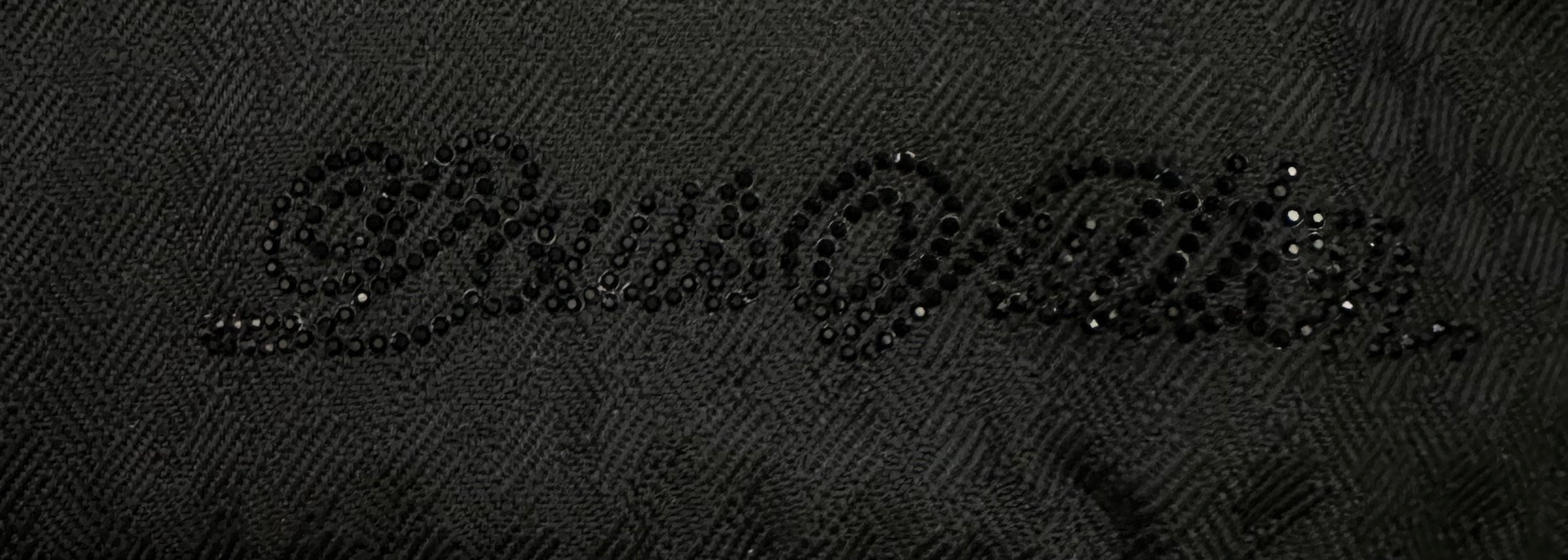 Black textured fabric close-up with embossed logo-style pattern