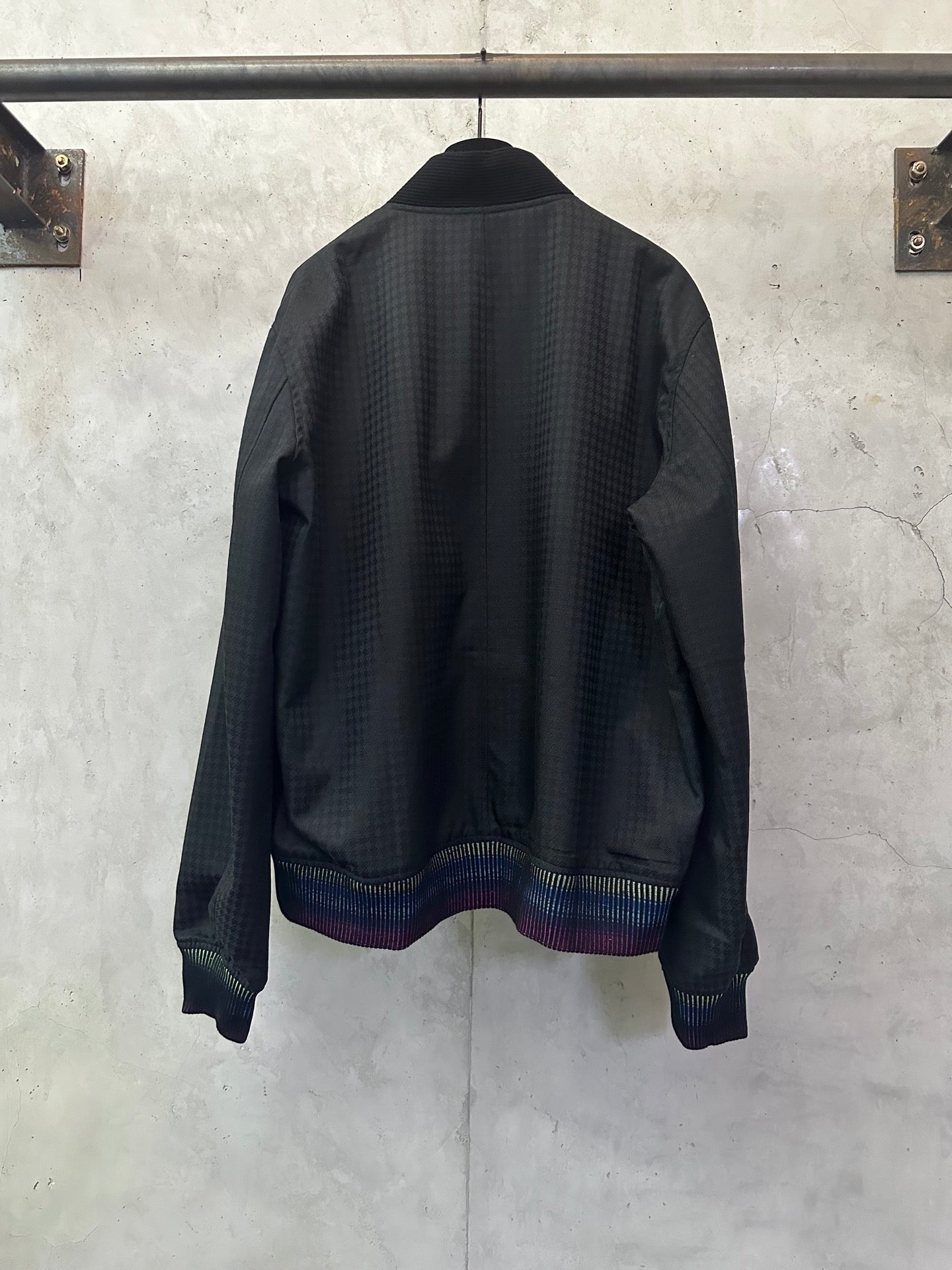 Long-sleeve jacket back view, dark fabric with multicolor striped ribbed hem