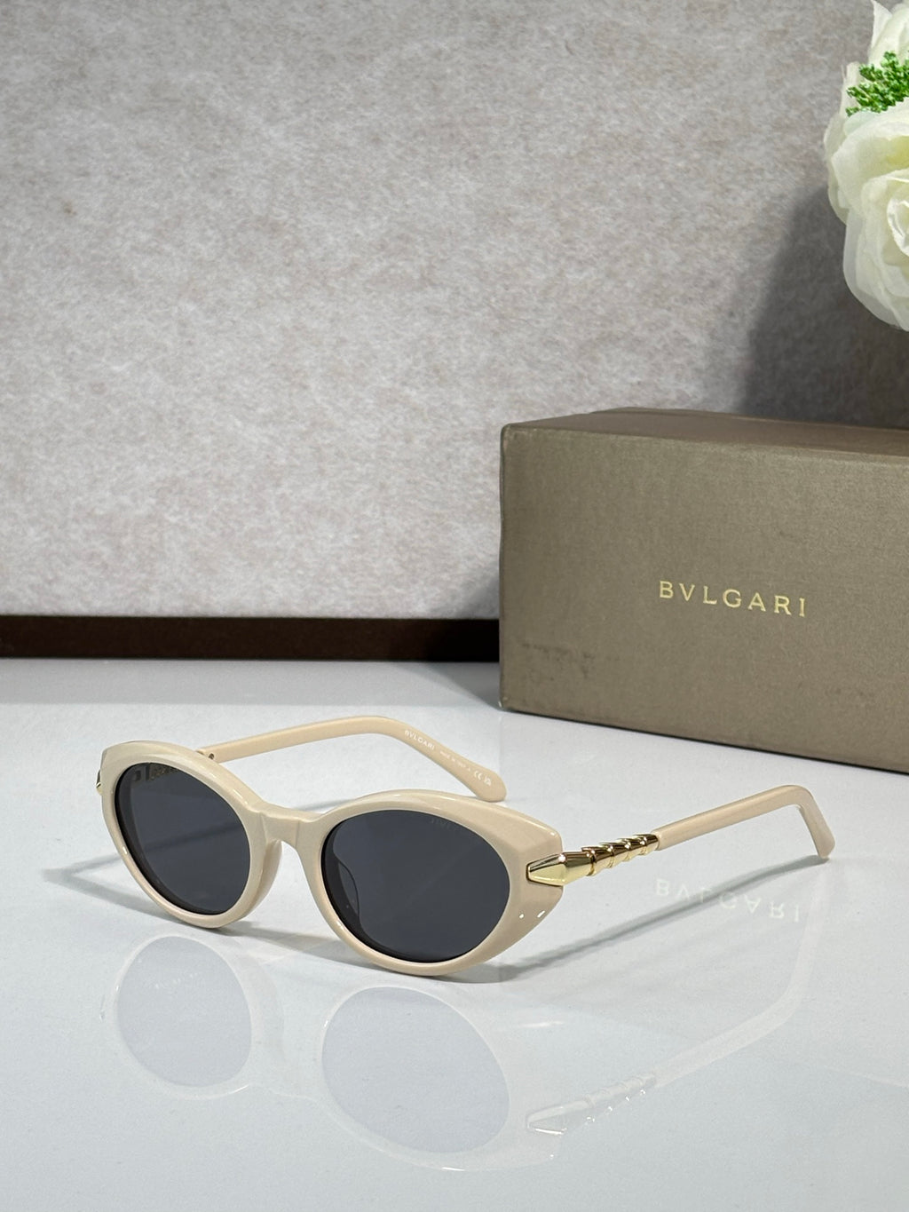 Cream sunglasses with dark tinted lenses and gold-tone temple details