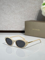 Cream sunglasses with dark tinted lenses and gold-tone temple details