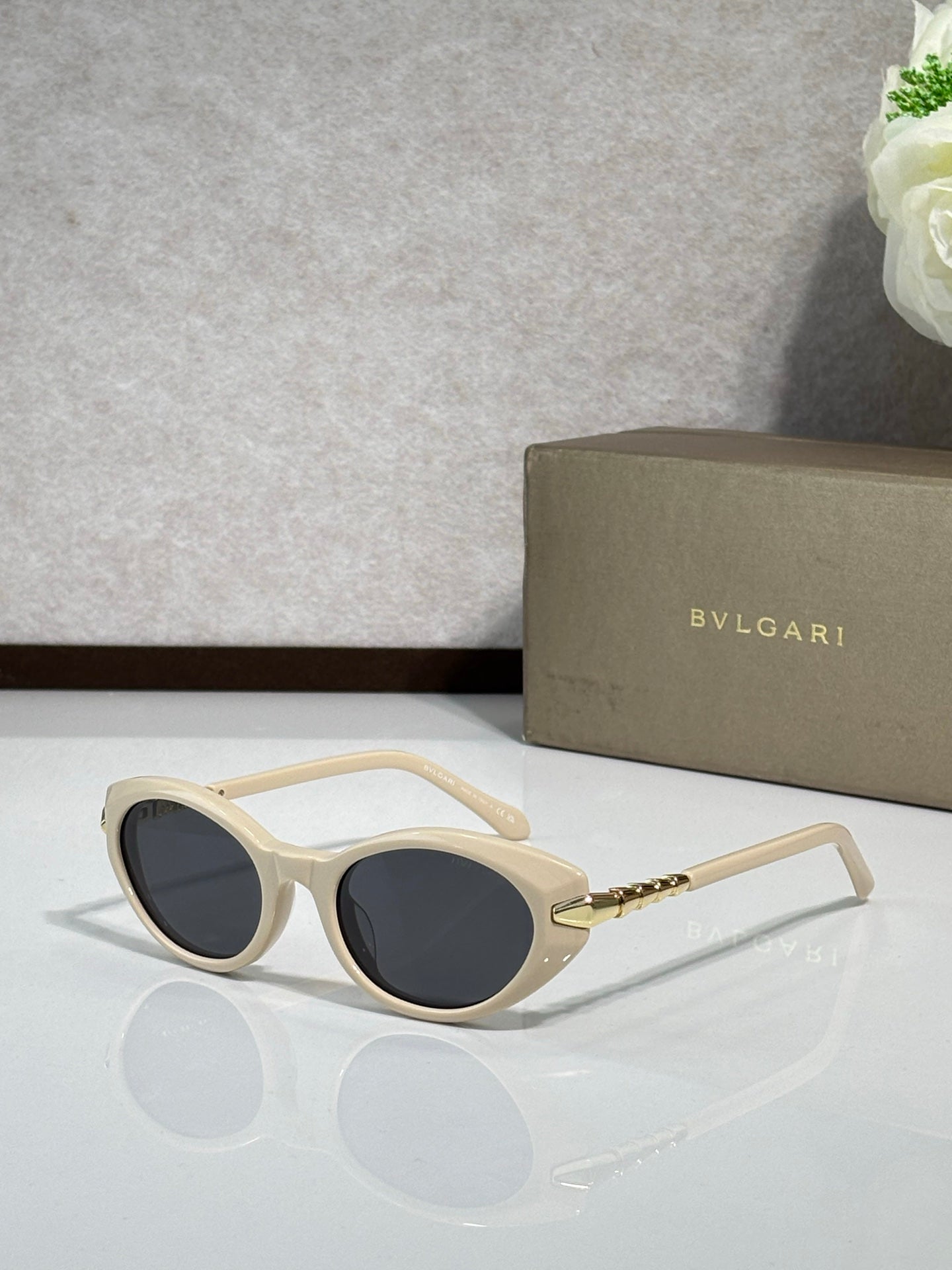 Cream sunglasses with dark tinted lenses and gold-tone temple details