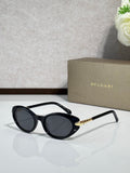 Black oval sunglasses with dark tinted lenses and gold logo temple arms