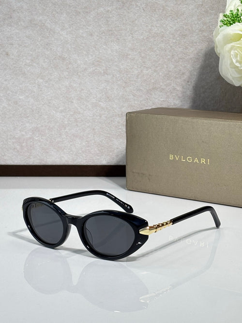 Black oval sunglasses with dark tinted lenses and gold logo temple arms