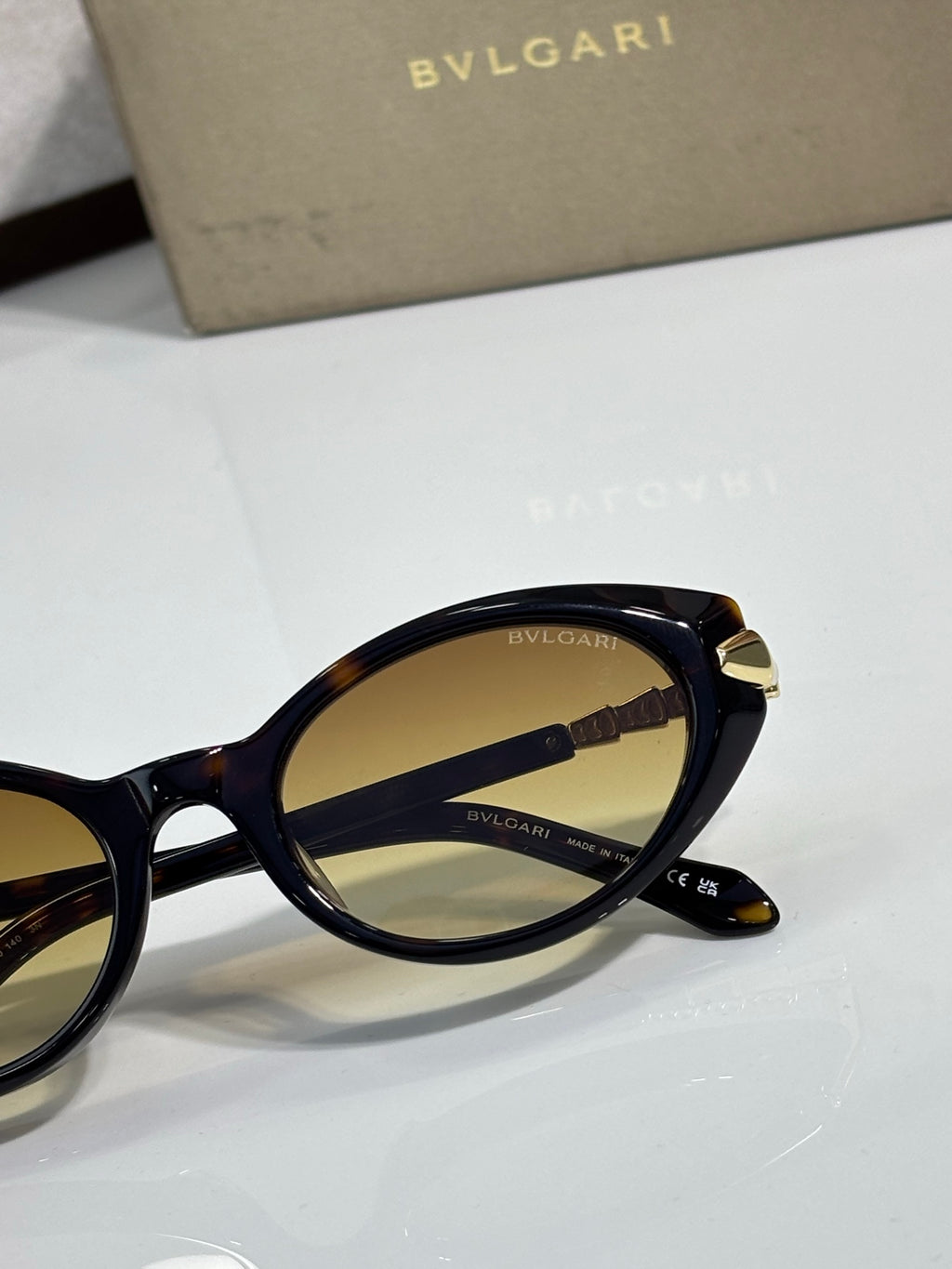 Navy/black sunglasses close-up with gold-tone temple tips and tinted lenses