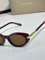 Burgundy sunglasses close-up with gold hinge detail and brown-tinted lens