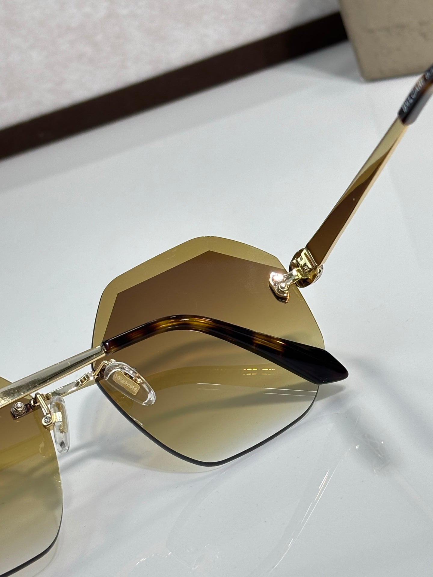 Sunglasses close-up with amber lenses and gold-tone frame, curved corner design.