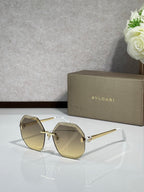 Sunglasses with amber lenses and gold-tone frame, curved octagon shape.