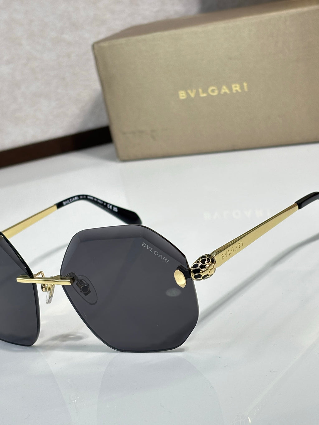 Sunglasses close-up: dark lenses with black frame and gold-tone details on bridge.