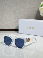 White cat-eye sunglasses with blue lenses and gold logo charm on the temple