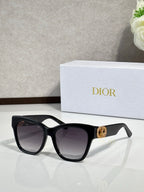 Black cat-eye sunglasses with dark lenses and gold logo charm at the temple