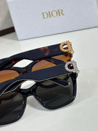 Stacked tortoiseshell and black sunglasses with gold and silver logo charms
