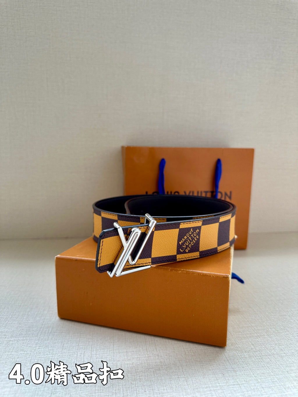 Louis Vuitton Damier check belt with gold buckle, laid across tan boxes