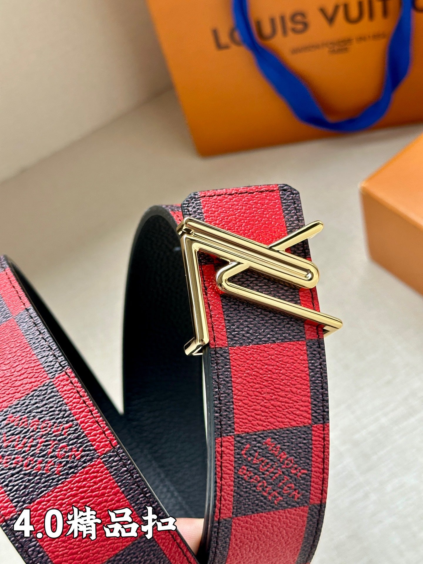 Metal V buckle on checked belt in red, navy, and gray tones